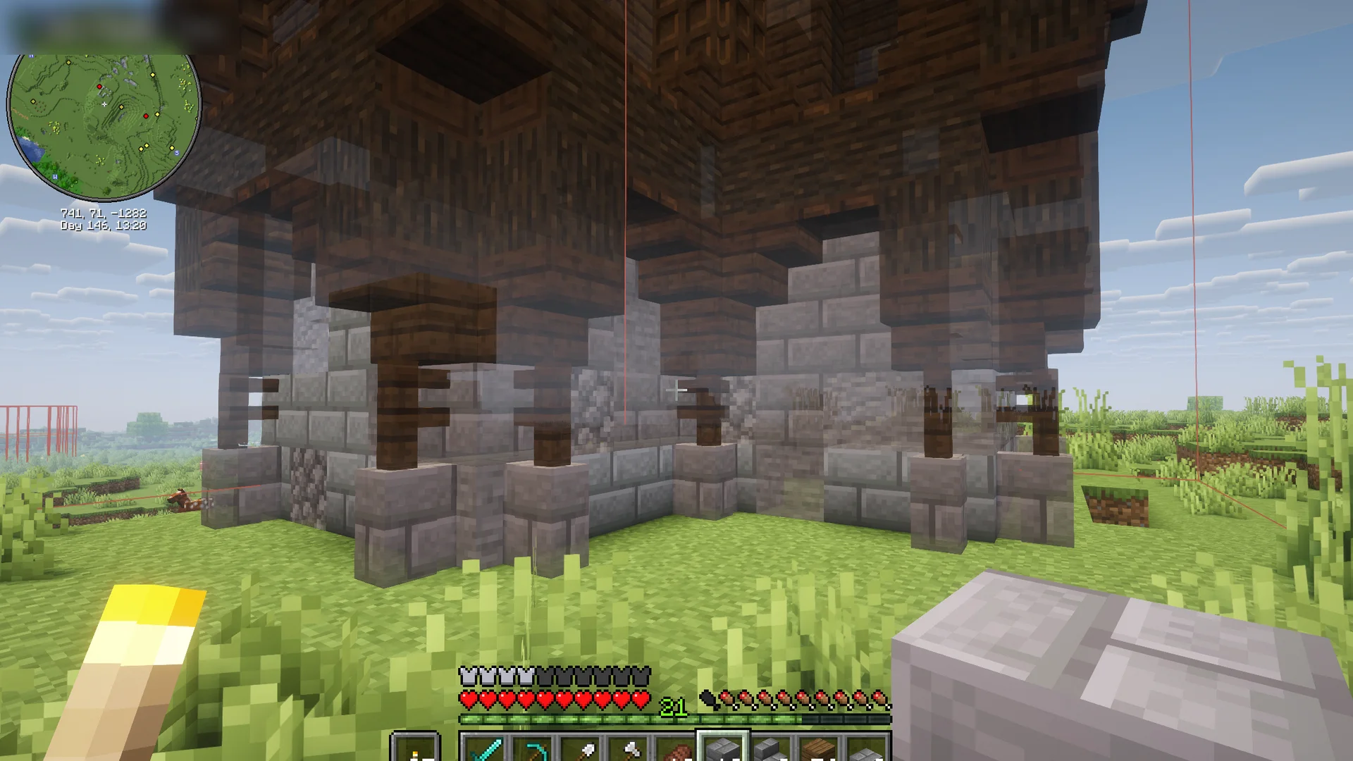 A schematic half built in Minecraft: real blocks below, see-through ghost blocks above showing what's left to build.
